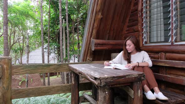 A beautiful young asian woman reading a book at home