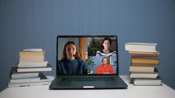 A Young Woman is Talking on a Video Call with a Young Man and a Woman