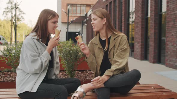 Happy Twin Sisters Enjoying Ice Cream Outside alt
