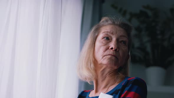 Pensive Old Woman Thinking Near the Big Window alt
