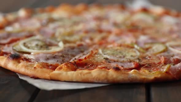Pizza with mozzarella cheese, salami, cucumber and onion, rotating close-up alt