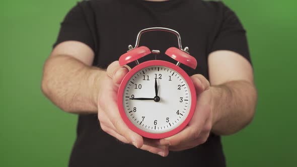 Caucasian Man in Black Tshirt Holding Vintage Red Alarm Clock in his Hands