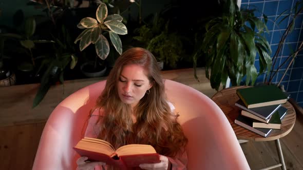 Girl Sitting In The Bathtub Without Water And Reads Book. alt