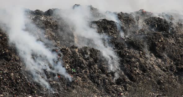 Close up of landfill with burning trash piles alt