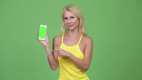 Young Happy Beautiful Blonde Woman Showing Phone and Giving Thumbs Up