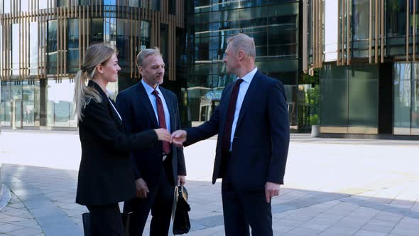 Businessmen and Businesswoman Meet a Colleague and Shake Hands Then Chat Together. Modern Office