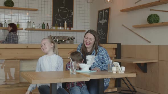 Joyful Kids with Mother Playing Funny Toy in Cafe alt