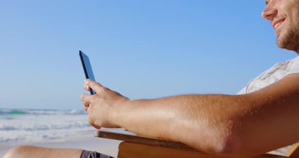 Man using mobile phone at beach in the sunshine 