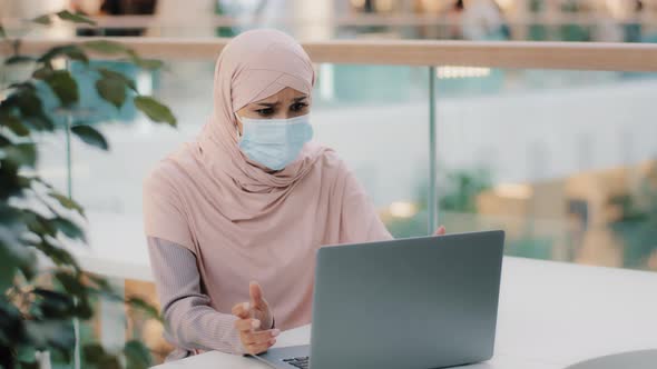 Young Arab Woman in Hijab Wearing Protective Mask Reading Email on Laptop Receiving Bad News Girl alt