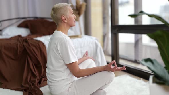 Senior Woman Practicing Yoga in Lotus Positionitting at Home