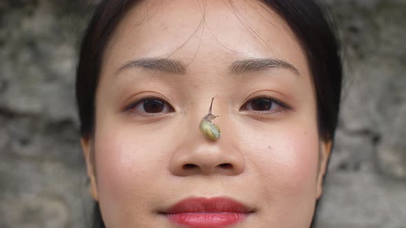 Serene woman with a snail on her nose