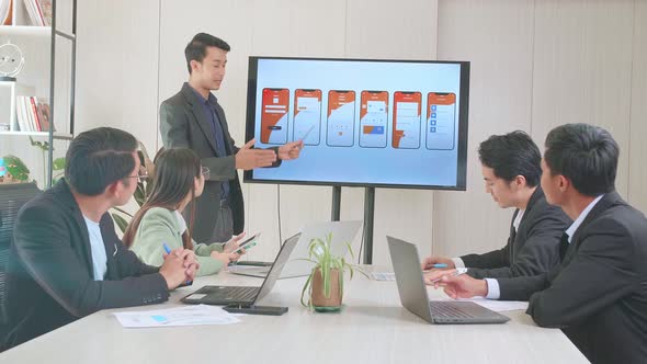 Young Asian Businessman Presentation To Business Colleagues About Mobile Application On Tv Screen alt