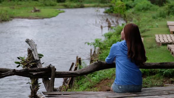 A young woman sitting by the river in rural village