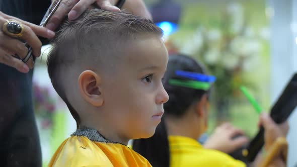 Children's Haircut in the Salon at the Time of the Coronavirus Epidemic. Little Boy Gets a Haircut alt