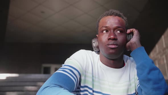 Black Young Man Listens to Music with Headphones