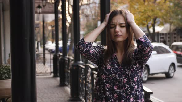 Close-up Portrait of a Young Businesswoman with Headache, a Girl Is Standing on the Street Tired alt