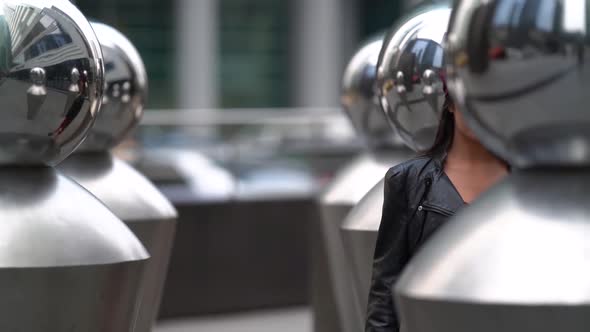 a Beautiful Female Model in a Purple Cap and Leather Jacket Poses in a Public Place Near Reflective alt