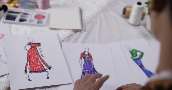 Close up hand of fashion designer man checking a sketch clothing paper alt