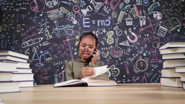 Front view of lazy Asian girl pretending to read book and using phone calling friend