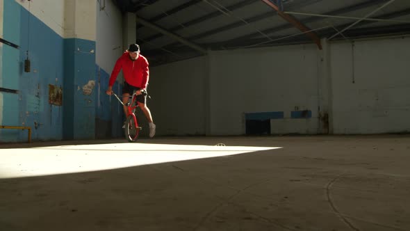 BMX rider in an empty warehouse alt
