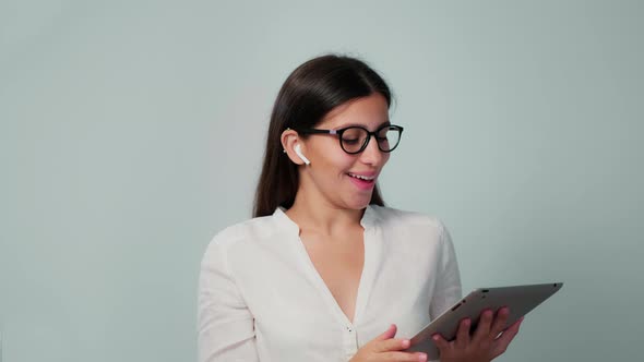 The Girl Communicates on Work in Headphones with a Tablet in Her Hands