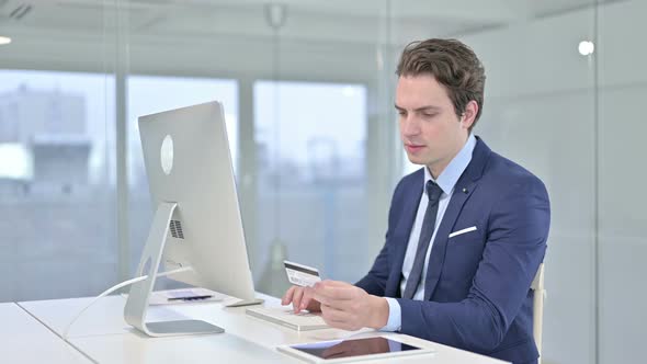 Focused Young Businessman Making Online Payment on Desk Top alt