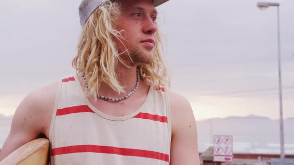 Caucasian male surfer holding a wooden surfboard alt