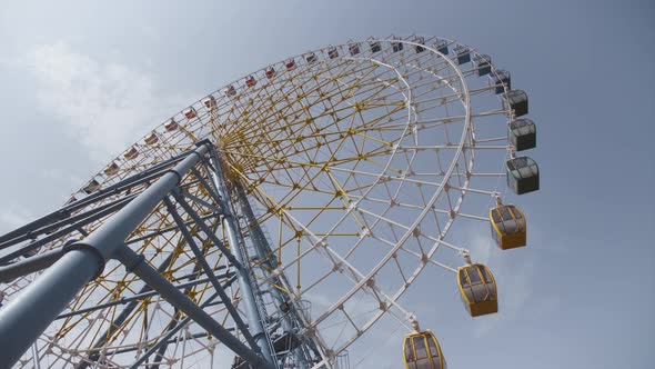 Big Ferris Wheel Rotates at Amusement Park Carnival Ride Over Clean Blue Sky