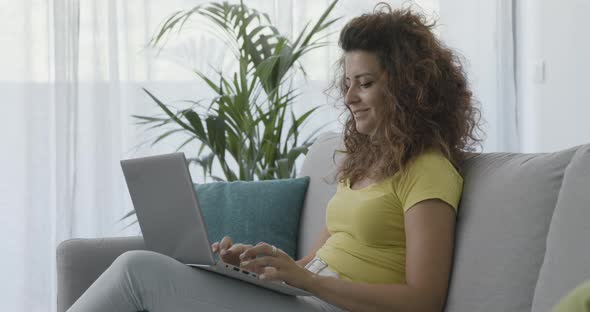 Woman sitting on the sofa and typing on her laptop