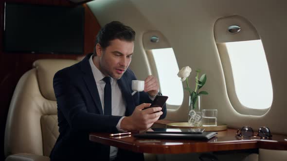 European Businessman Typing Phone on Airplane Trip alt