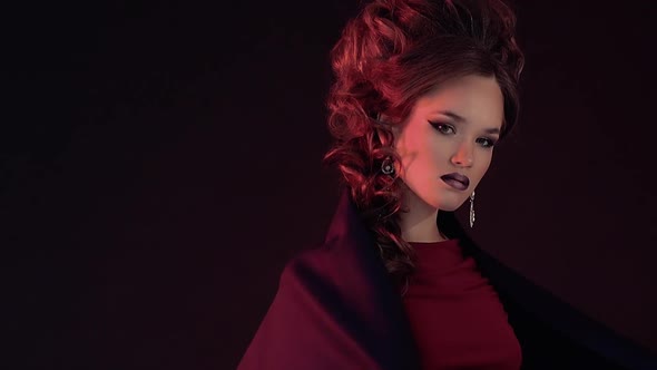 Portrait of a Young Beautiful Girl in a Red Dress Enlightening in Red Light She Covers Herself with alt