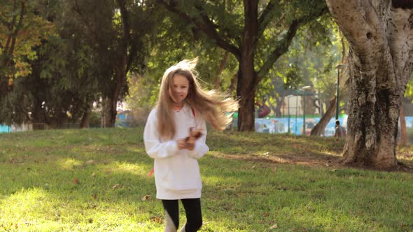 Cute Girl Collecting Autumn Leaves in Park