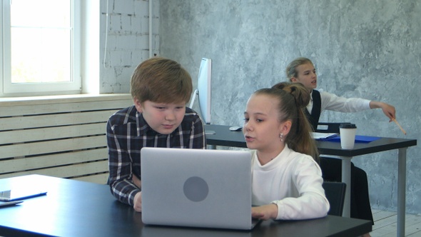 Two little business kids discussing and working on laptop