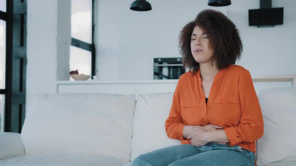 Stressed African American Woman Sitting on Sofa Touching Belly Ill Sick Biracial Curly Girl alt