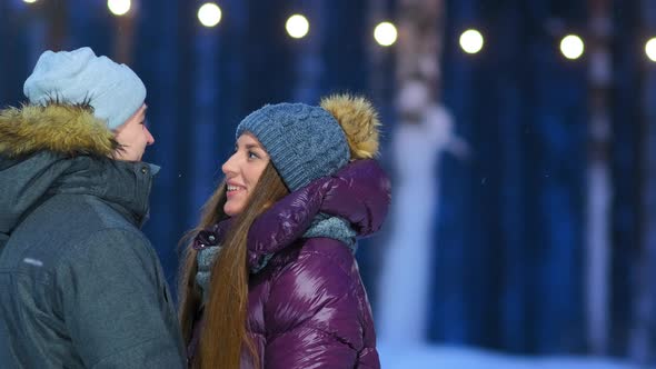 Lovely Couple in Warm Jackets Talks on Public Skating Rink