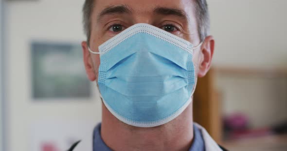 Portrait of caucasian teacher puttin on face mask while in classroom alt
