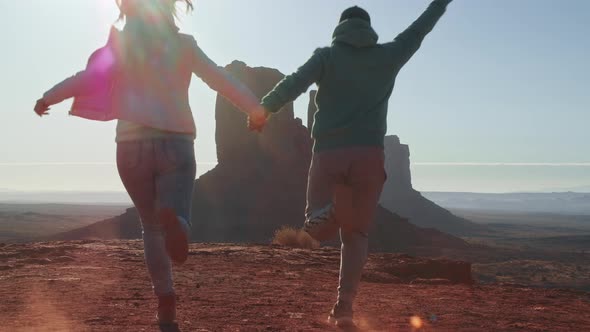 Happy Couple on Vacation Trip Running in Monument Valley Jumping Raising Arms alt