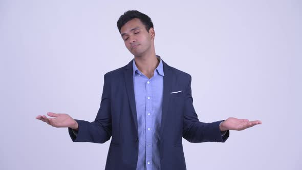 Happy Young Indian Businessman Comparing Something alt