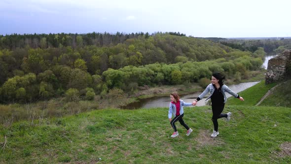 Mother and daughter run on the coast Sluch river hills