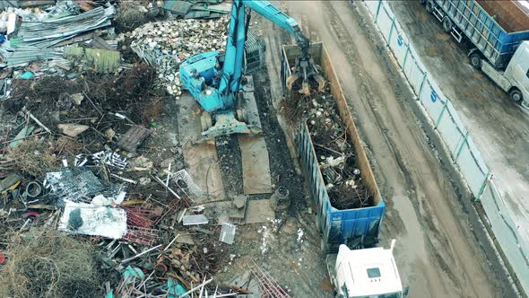 Industrial Vehicle is Putting Scrap Metal Into Truck's Container alt