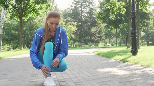 Beautiful Sportswoman Tying Her Shoelaces Before Running in the Park alt