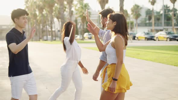 Happy Diverse Friends Greeting Each Other Outdoors on Alley with Palm Trees alt
