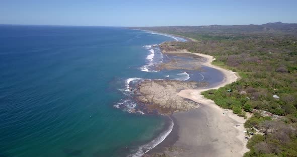 Aerial drone view of the beach, rocks and tide pools in Playa Palada, Guiones, Nosara, Costa Rica alt