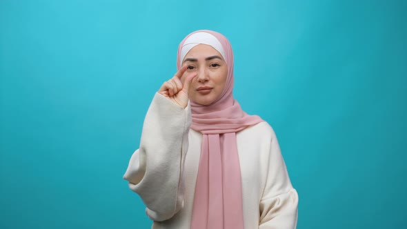 Disappointed Unhappy Young Muslim Woman in Hijab Doing a Little Bit Gesture with Fingers
