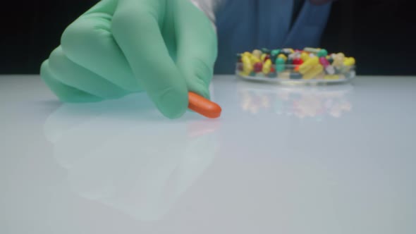 Lab Worker Moving Orange Pill to Camera alt