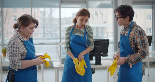 Diverse Team of Janitor Putting on Rubber Gloves Preparing To Clean Office alt