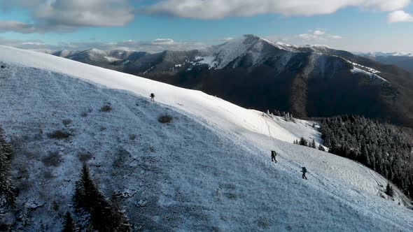 Hiker Friends Walking on Snow Covered Mountain Ridge