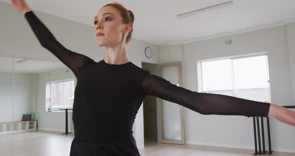 Caucasian female ballet dancer practicing ballet during a dance class in a bright studio alt