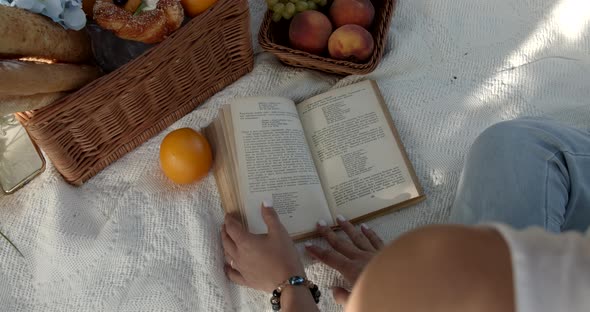Girl Flips Through A Book On A Picnic In The Garden alt