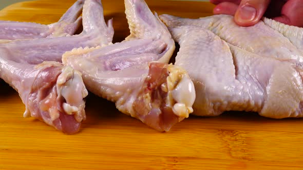 Fresh chicken wings are laid out on a cutting board alt